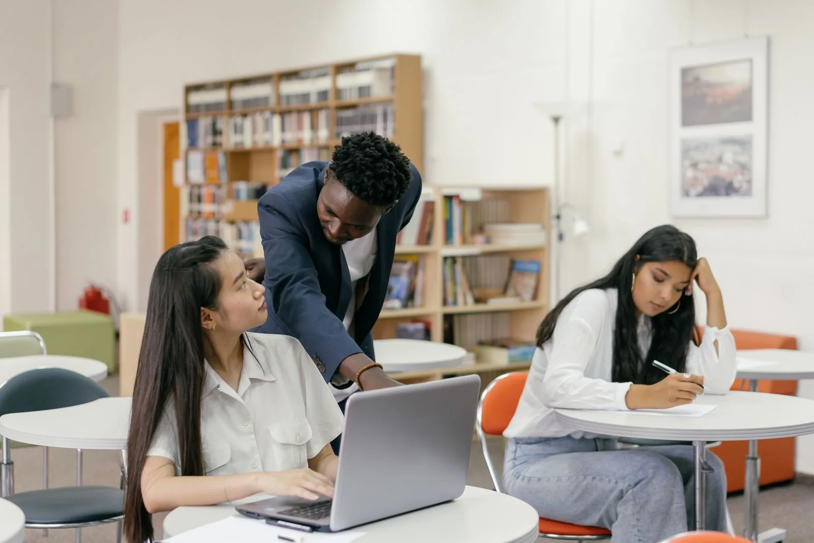 A tutor guiding a student on her laptop in a bright, modern study space