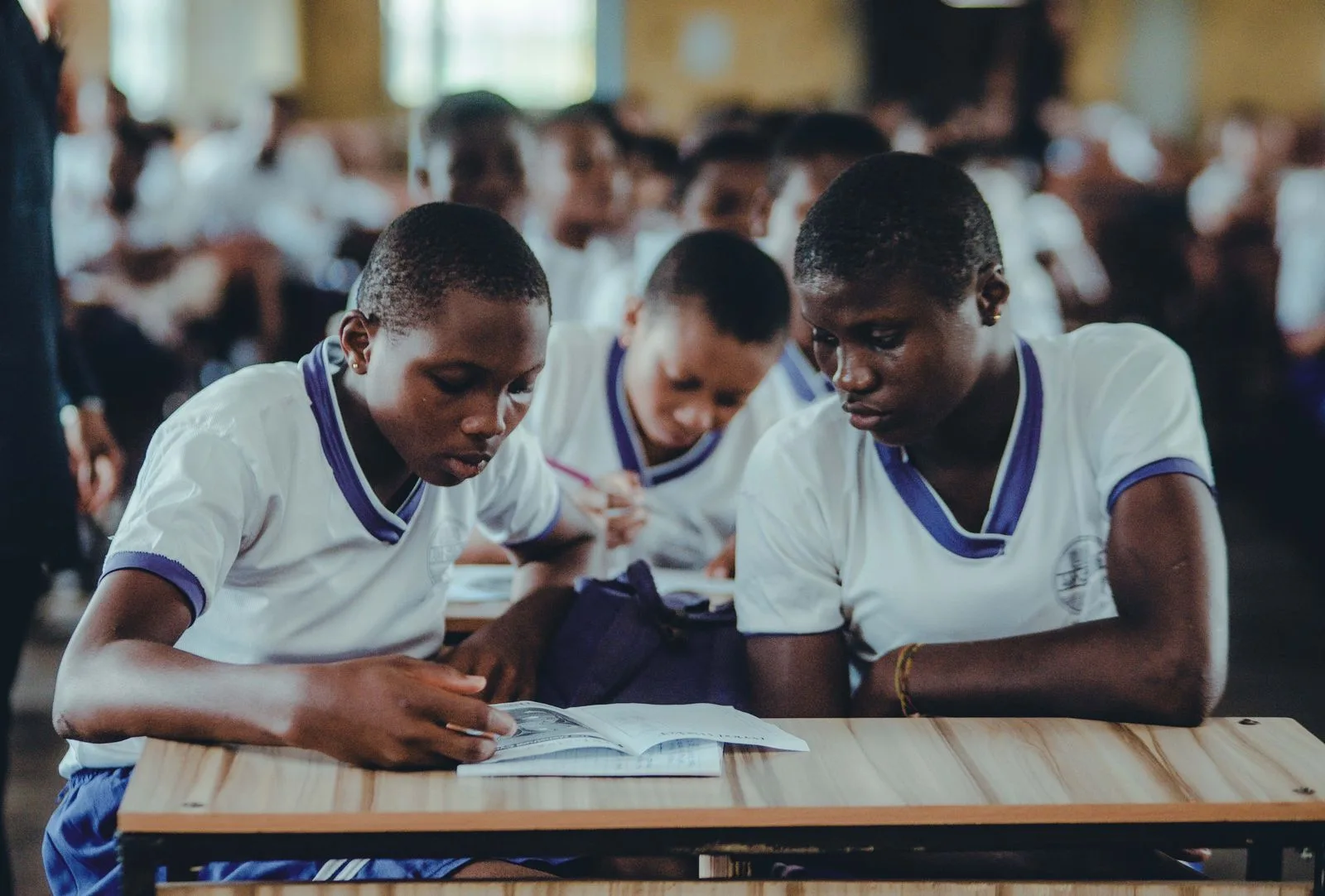 African secondary school students in uniform, focused on their studies together at a shared desk