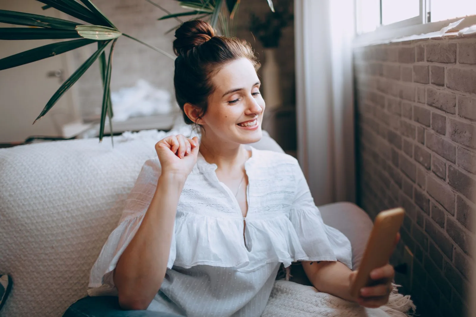 A parent smiling at a message on her phone at home